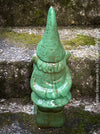Green garden gnome figurine on a stone surface for sale at TOMs FLOWer CLUB.