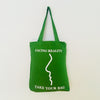Green tote bag with text and a face outline on a white background