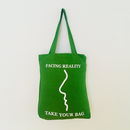 Green tote bag with text and a face outline on a white background