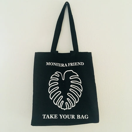 Black TAKE YOUR BAG made of 100% organic cotton, NEUTRAL® and FAIRTRADE® certified with white MONSTERA FRIEND design.