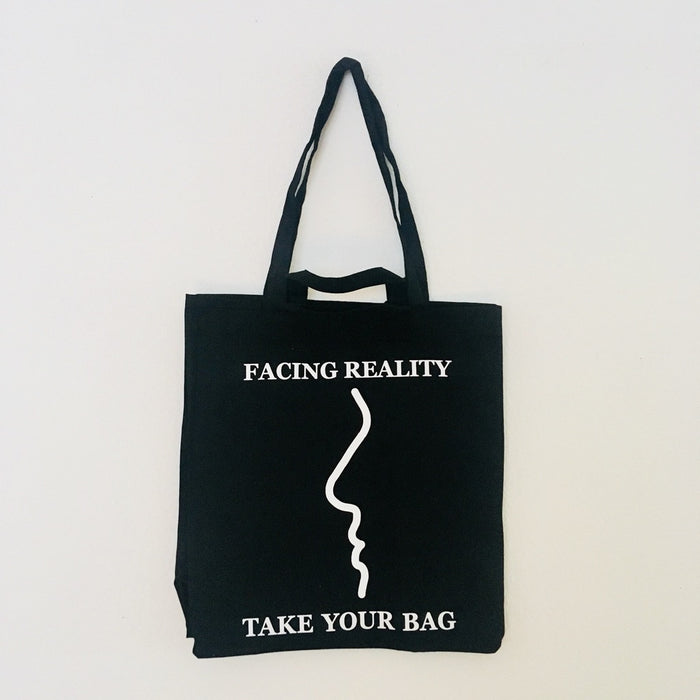 Black TAKE YOUR BAG made of 100% organic cotton, NEUTRAL® and FAIRTRADE® certified with white FACING REALITY design.