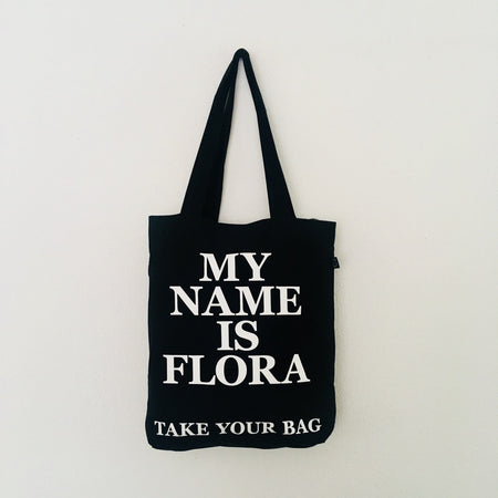 Black TAKE YOUR BAG with white MY NAME IS FLORA design by TOMs FLOWer CLUB made of 100% organic cotton, EarthPositive® certified, various colours, Swiss designed, premium quality, world wide shipping.