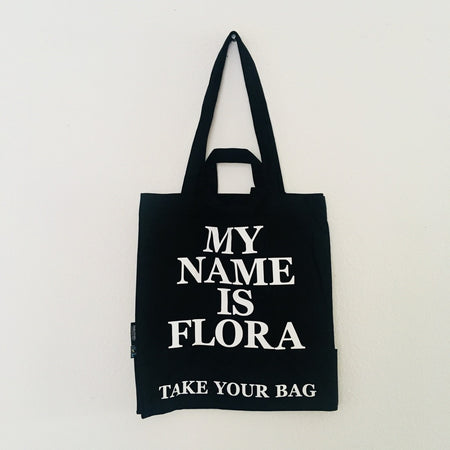 Black TAKE YOUR BAG made of 100% organic cotton, NEUTRAL® and FAIRTRADE® certified with white MY NAME IS FLORA design.