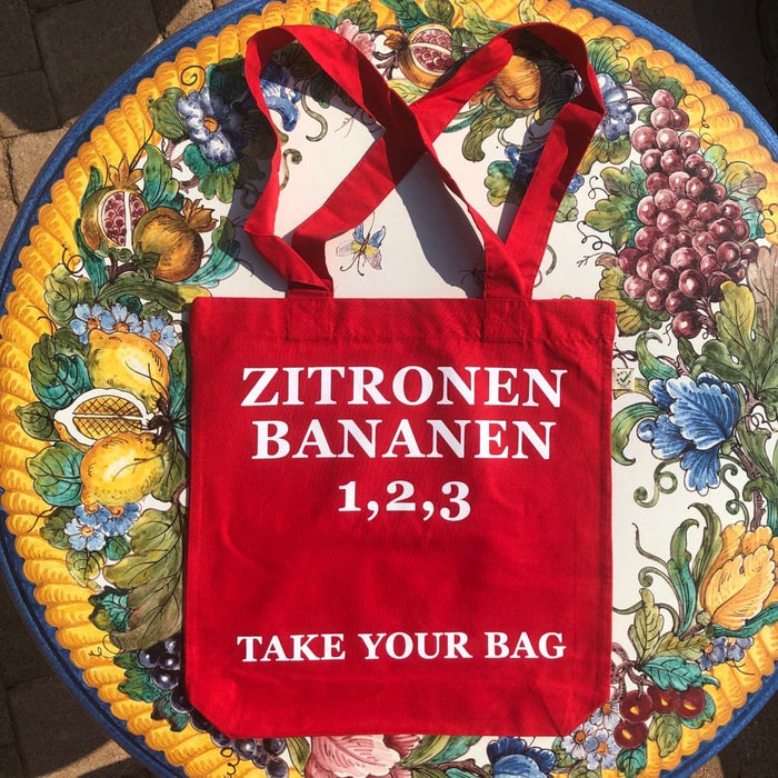 Red TAKE YOUR BAG with white ZITRONEN, BANANEN, 1,2,3 design by TOMs FLOWer CLUB made of 100% organic cotton, EarthPositive® certified, various colours, Swiss designed, premium quality, world wide shipping.