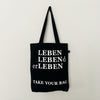 Black TAKE YOUR BAG with white LEBEN LEBENd erLEBEN design by TOMs FLOWer CLUB made of 100% organic cotton, EarthPositive® certified, various colours, Swiss designed, premium quality, world wide shipping.
