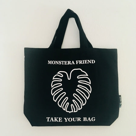 Black TAKE YOUR BAG with white MONSTERA FRIEND design made of 100% organic cotton, NEUTRAL® and FAIRTRADE® certified, Monstera, Monstera friend, Baumwolltasche, Stofftasche, tote bag, shopping bag, TOMs FLOWer CLUB, TAKE YOUR BAG, organic cotton, bio Baumwolle. Einkaufen, Einkaufstasche 
