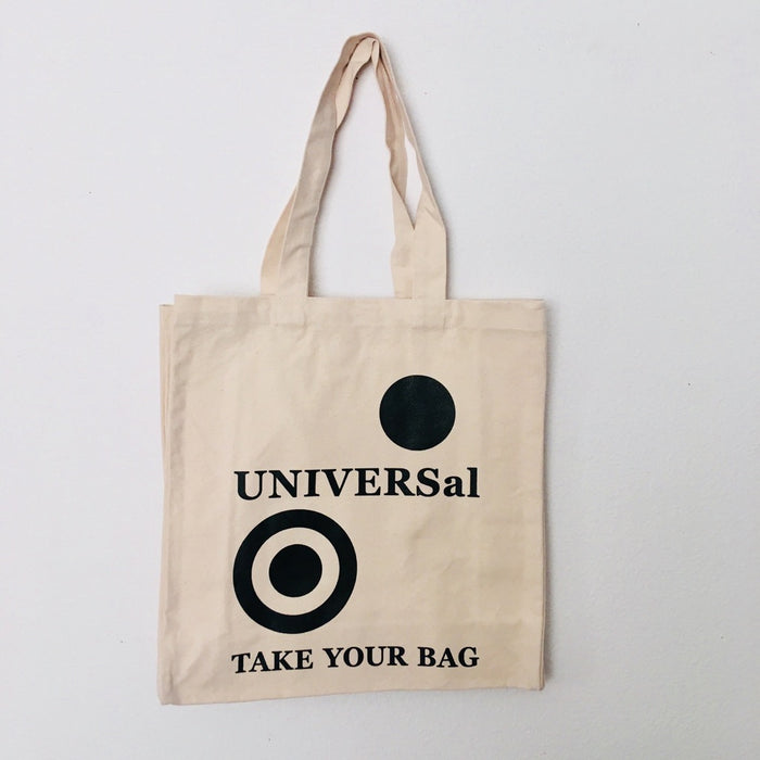 A beige cotton tote bag with a black 'UNIVERSal' logo and the text 'TAKE YOUR BAG' printed on the front.