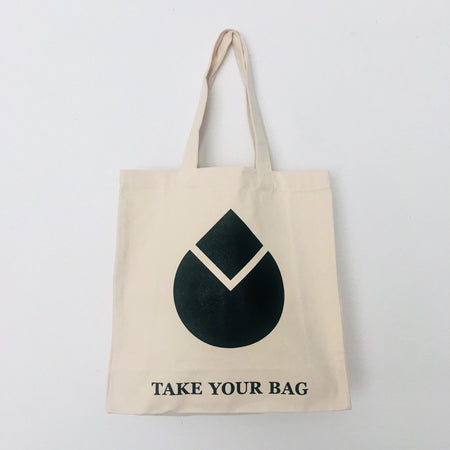 A beige cotton canvas bag with a black water drop design and the text 'TAKE YOUR BAG' on the bottom.