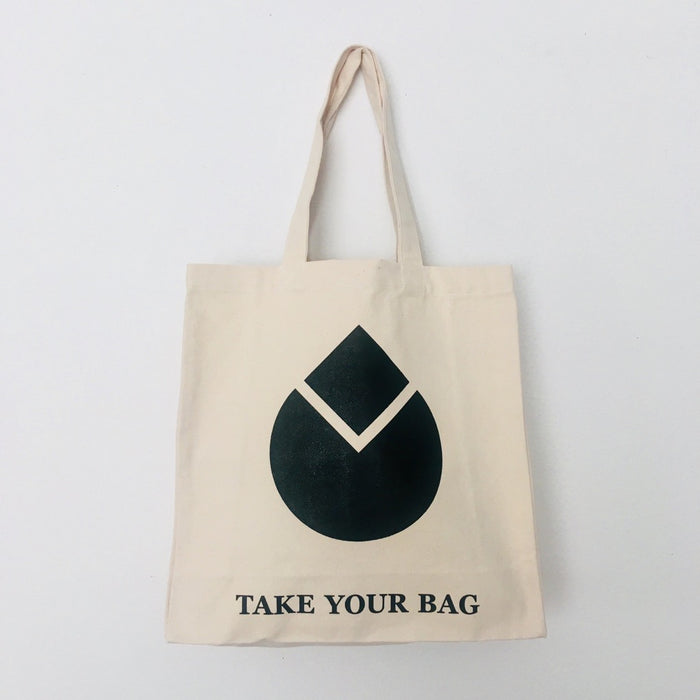A beige cotton canvas bag with a black water drop design and the text 'TAKE YOUR BAG' on the bottom.